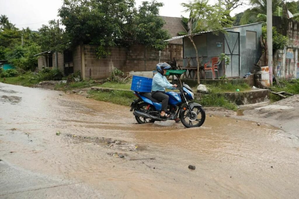 Un hombre en una motocicleta cruza una calle inundada debido a fuertes lluvias, el pasado 21 de junio del 2024, en Soyapango, El Salvador.