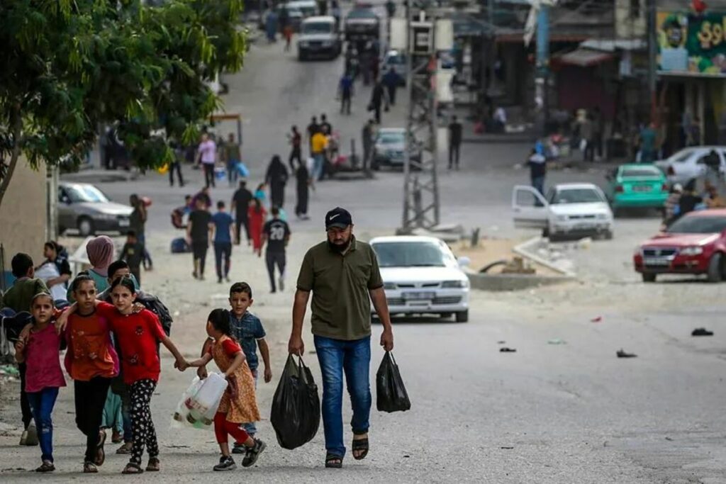 Un palestino que transporta comida camina con sus hijos en el barrio de Al Shejaeiya, al este de la ciudad de Gaza.